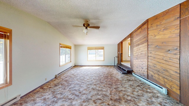 906 11th St E, Polson, MT 59860 - unfurnished living room featuring a baseboard heating unit, a textured ceiling, a ceiling fan, carpet, and wood walls