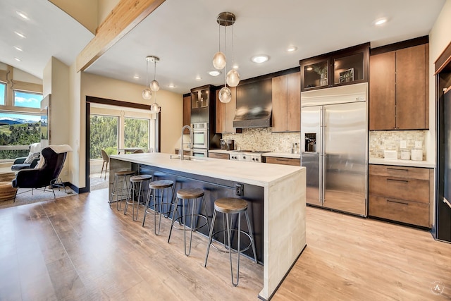 162 Jackson Creek Rd, Montana City, MT 59634 - kitchen with stainless steel appliances, a breakfast bar area, light wood-style floors, a kitchen island with sink, and recessed lighting