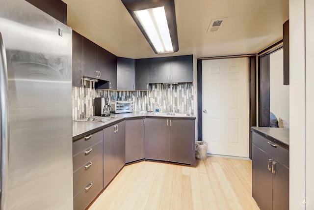 162 Jackson Creek Rd, Montana City, MT 59634 - kitchen with freestanding refrigerator, light wood-style floors, electric cooktop, tasteful backsplash, and dark countertops