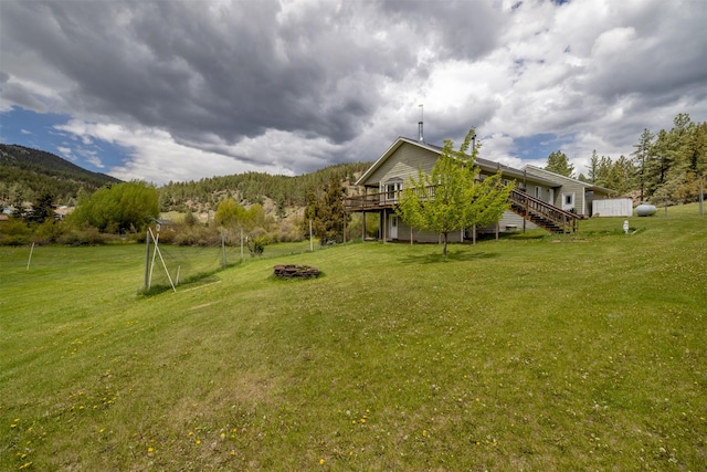 7551 York Rd, Helena, MT 59602 - view of grassy yard with a deck with mountain view, a fire pit, and stairway