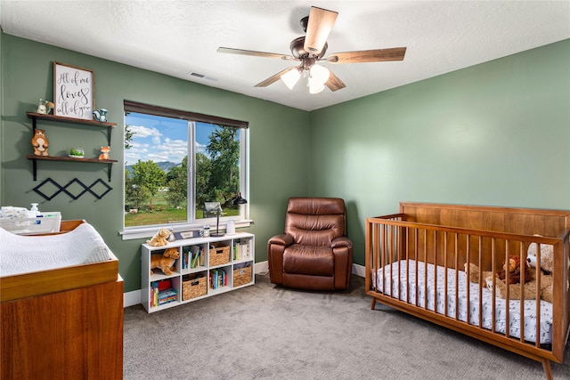 380 Stonybrook Dr, Missoula, MT 59804 - carpeted bedroom with a crib, ceiling fan, baseboards, and a textured ceiling