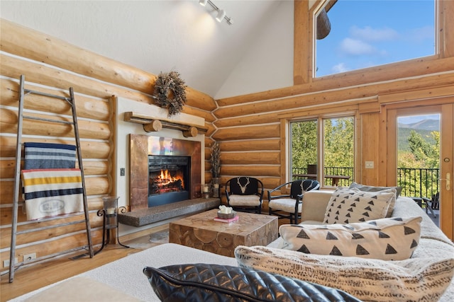 970 Colorado Ave, Whitefish, MT 59937 - living room featuring high vaulted ceiling, wood finished floors, rail lighting, log walls, and a lit fireplace
