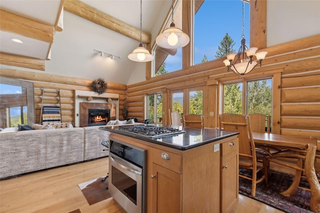 970 Colorado Ave, Whitefish, MT 59937 - kitchen with stainless steel appliances, log walls, high vaulted ceiling, plenty of natural light, and light wood-type flooring
