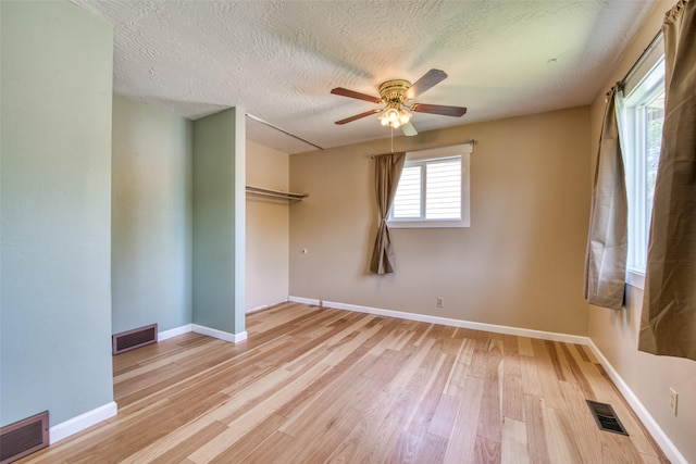 229 Glacier Dr, Lolo, MT 59847 - unfurnished bedroom featuring light wood finished floors, baseboards, a textured ceiling, a closet, and ceiling fan