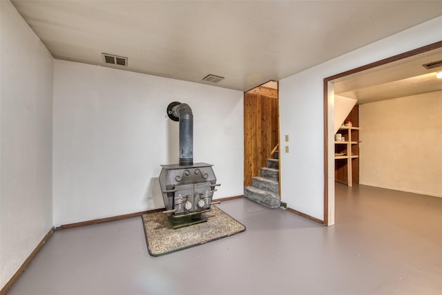 229 Glacier Dr, Lolo, MT 59847 - unfurnished living room featuring a wood stove, concrete floors, stairs, and baseboards
