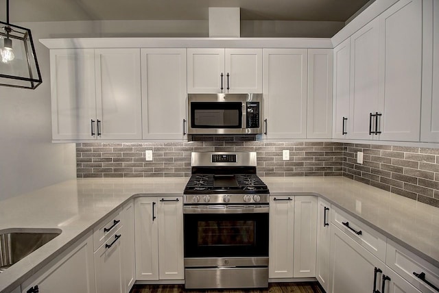 178 Meadow Vista Loop Unit A, Kalispell, MT 59901 - kitchen featuring appliances with stainless steel finishes, white cabinetry, tasteful backsplash, and hanging light fixtures