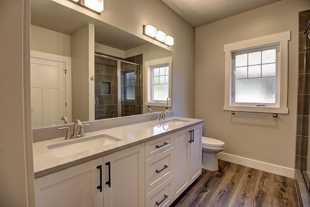178 Meadow Vista Loop Unit A, Kalispell, MT 59901 - bathroom with double vanity, tiled shower, toilet, wood finished floors, and baseboards