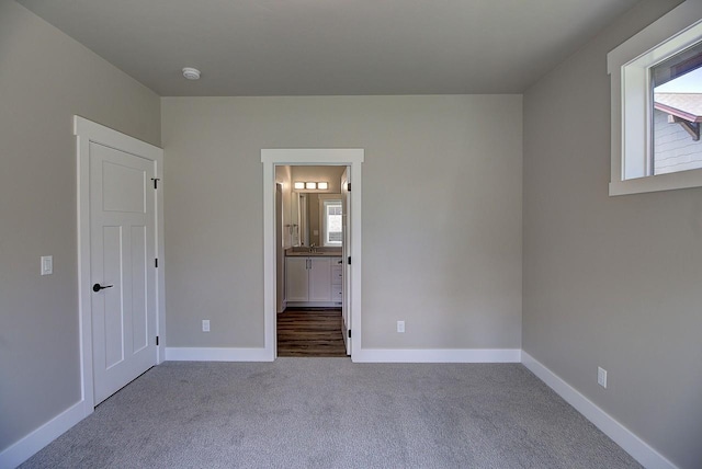 178 Meadow Vista Loop Unit A, Kalispell, MT 59901 - unfurnished bedroom featuring multiple windows, carpet floors, baseboards, and connected bathroom
