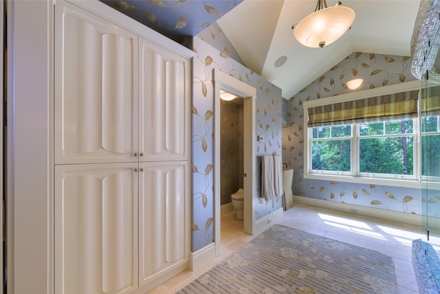33702 N Finley Point Rd, Polson, MT 59860 - full bathroom featuring wallpapered walls, vaulted ceiling, toilet, tile patterned floors, and baseboards