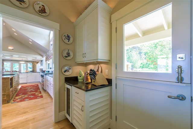 33702 N Finley Point Rd, Polson, MT 59860 - kitchen with lofted ceiling, white cabinetry, light wood-style floors, dark countertops, and beverage cooler