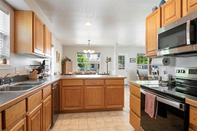 409 Bentley Park Loop, Missoula, MT 59801 - kitchen with appliances with stainless steel finishes, a chandelier, a peninsula, a textured ceiling, and pendant lighting