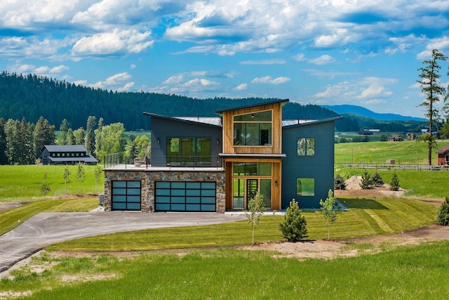 165 River Ranch Rd, Whitefish, MT 59937 - modern home with a balcony, an attached garage, driveway, a mountain view, and a view of trees