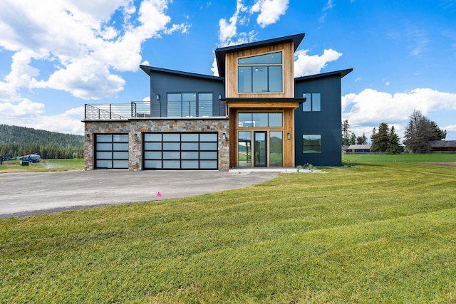 165 River Ranch Rd, Whitefish, MT 59937 - contemporary house with a front lawn, asphalt driveway, stone siding, a garage, and a balcony