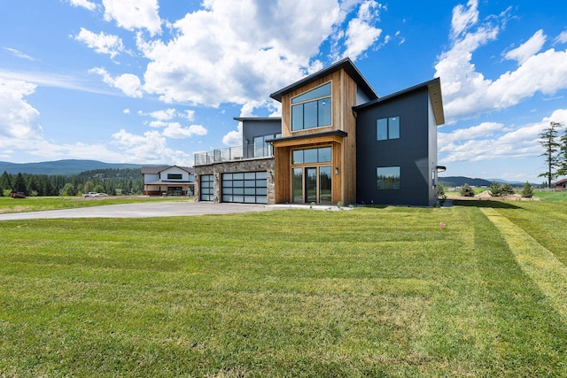 165 River Ranch Rd, Whitefish, MT 59937 - back of house with driveway, an attached garage, a balcony, a mountain view, and a yard