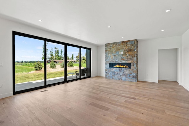 165 River Ranch Rd, Whitefish, MT 59937 - unfurnished living room with light wood-style flooring, a stone fireplace, baseboards, and recessed lighting