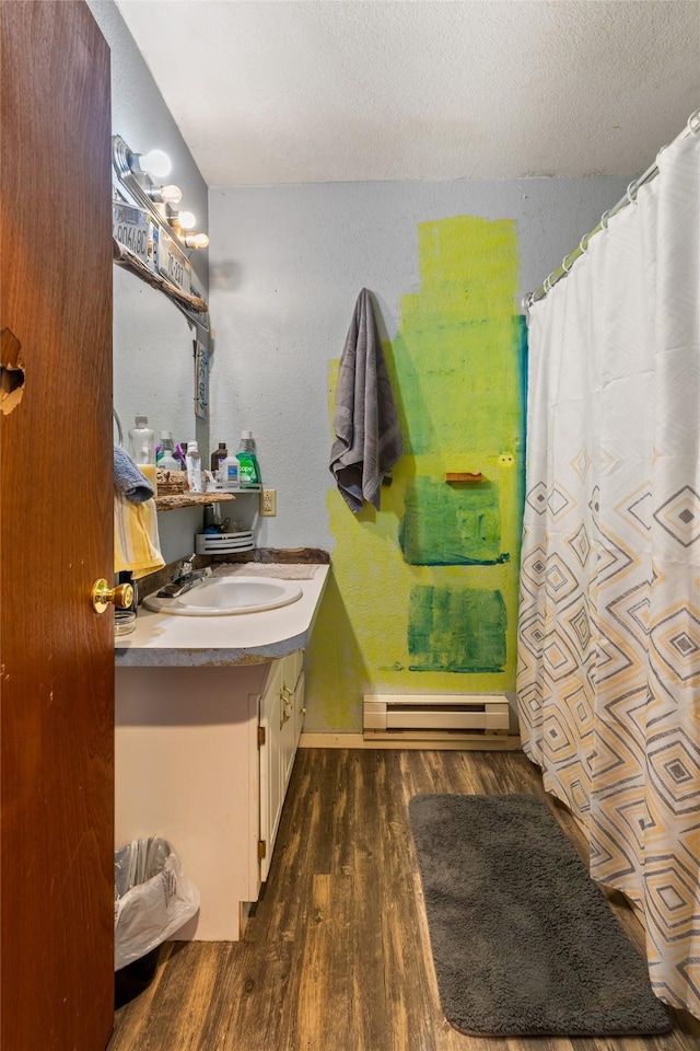 1319 3rd St, Whitefish, MT 59937 - full bathroom with a baseboard radiator, wood finished floors, vanity, a textured ceiling, and a shower with shower curtain