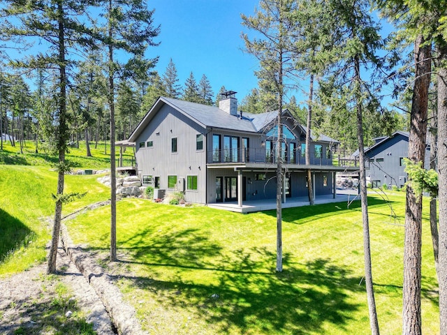 148 Blacktail Loop, Lakeside, MT 59922 - back of property featuring a chimney, a deck, a lawn, and board and batten siding