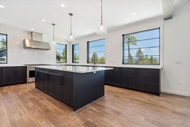 148 Blacktail Loop, Lakeside, MT 59922 - kitchen featuring dark cabinets, wall chimney range hood, light countertops, high end stainless steel range oven, and a kitchen island