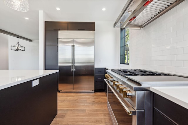148 Blacktail Loop, Lakeside, MT 59922 - kitchen featuring high end appliances, light countertops, custom exhaust hood, light wood-style floors, and tasteful backsplash