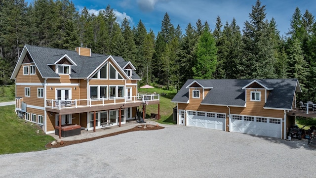 115 Wagon Wheel Rd, Whitefish, MT 59937 - view of front of property featuring a wooden deck, a chimney, gravel driveway, a forest view, and a shingled roof
