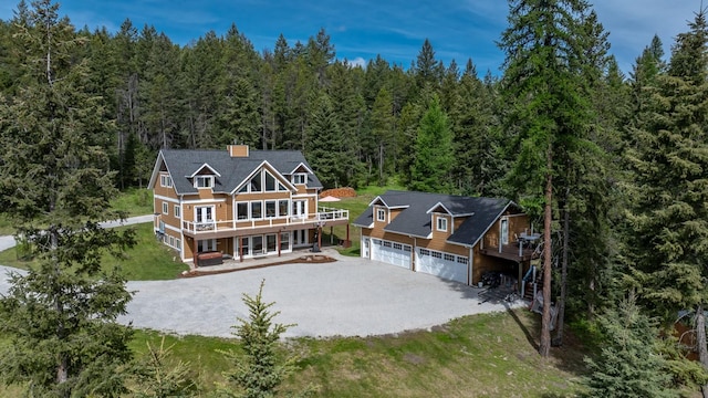 115 Wagon Wheel Rd, Whitefish, MT 59937 - rear view of house with a forest view, driveway, a garage, a deck, and a yard