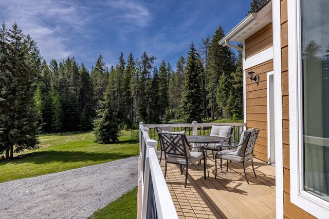 115 Wagon Wheel Rd, Whitefish, MT 59937 - wooden terrace featuring outdoor dining area, a lawn, and a view of trees