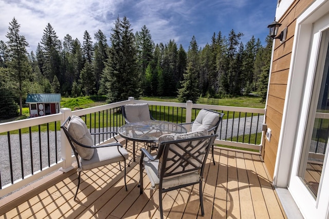 115 Wagon Wheel Rd, Whitefish, MT 59937 - wooden terrace with a forest view, outdoor dining area, a yard, and an outdoor structure