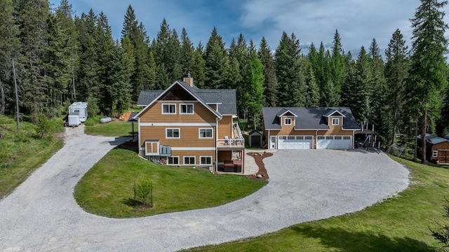 115 Wagon Wheel Rd, Whitefish, MT 59937 - view of front of house with gravel driveway, a wooded view, a garage, a chimney, and a front lawn