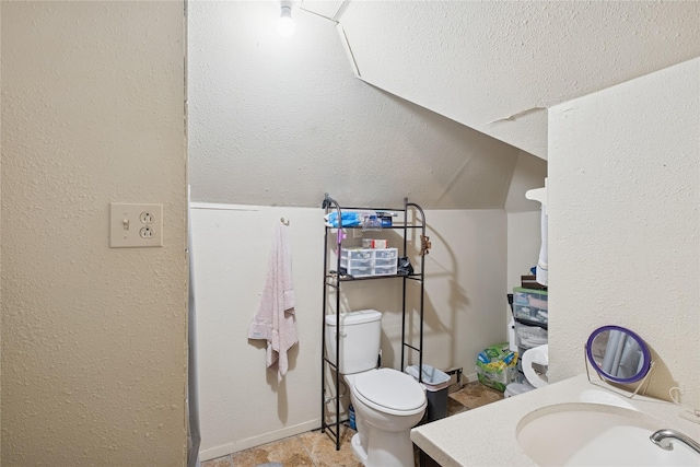44 5th Ave E, Kalispell, MT 59901 - bathroom with toilet, vanity, vaulted ceiling, and baseboards