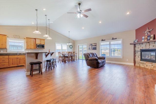 7567 Kingpost Loop, Helena, MT 59602 - living room with light wood-type flooring, ceiling fan, a fireplace, high vaulted ceiling, and baseboards