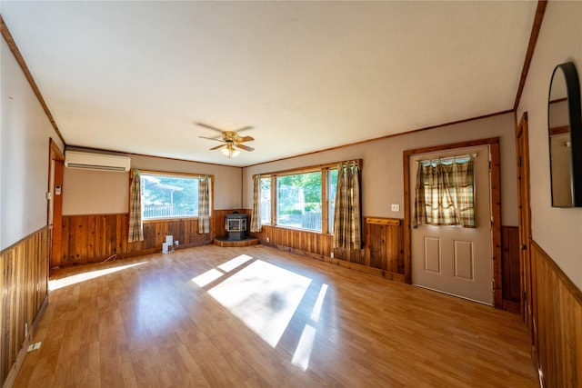 411 Colorado Ave, Libby, MT 59923 - unfurnished living room with wainscoting, a wall mounted air conditioner, a wood stove, wooden walls, and wood finished floors