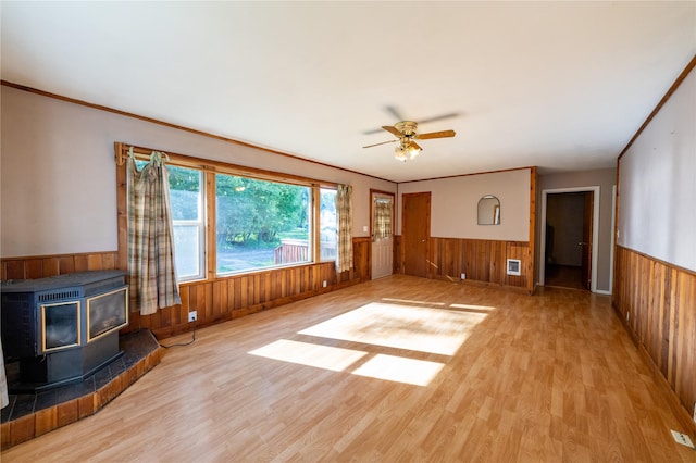 411 Colorado Ave, Libby, MT 59923 - unfurnished living room featuring wainscoting, wooden walls, a wood stove, wood finished floors, and ceiling fan