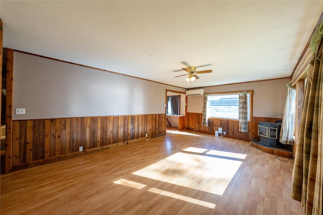 411 Colorado Ave, Libby, MT 59923 - unfurnished living room featuring a wood stove, a wainscoted wall, a wall unit AC, wood finished floors, and wood walls
