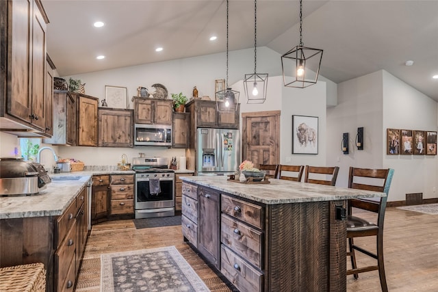 224 Forest Edge Trl, Kalispell, MT 59901 - kitchen featuring stainless steel appliances, a breakfast bar area, light wood-style flooring, a center island, and high vaulted ceiling