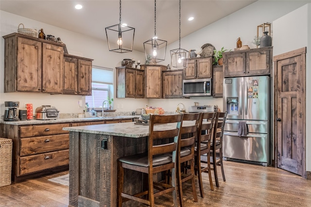 224 Forest Edge Trl, Kalispell, MT 59901 - kitchen featuring appliances with stainless steel finishes, wood finished floors, a kitchen island, a breakfast bar area, and pendant lighting