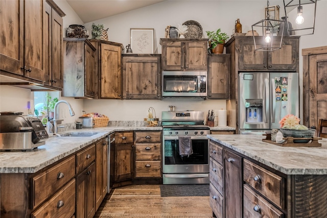 224 Forest Edge Trl, Kalispell, MT 59901 - kitchen featuring appliances with stainless steel finishes, lofted ceiling, wood finished floors, decorative light fixtures, and dark brown cabinetry