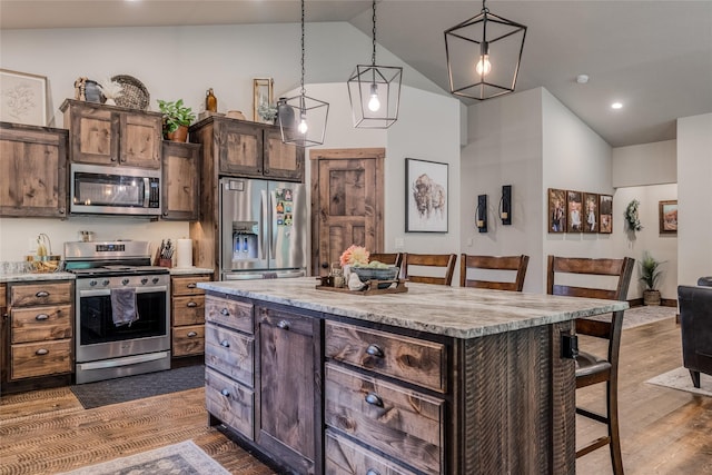 224 Forest Edge Trl, Kalispell, MT 59901 - kitchen featuring appliances with stainless steel finishes, vaulted ceiling, a breakfast bar area, dark wood-style flooring, and a kitchen island
