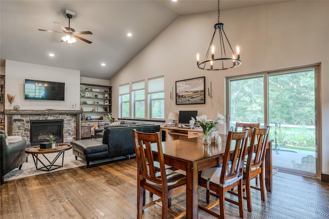 224 Forest Edge Trl, Kalispell, MT 59901 - dining space featuring high vaulted ceiling, dark wood-style flooring, a chandelier, a stone fireplace, and ceiling fan