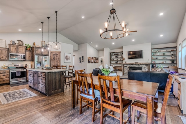 224 Forest Edge Trl, Kalispell, MT 59901 - dining area with lofted ceiling, dark wood-style flooring, a chandelier, a fireplace, and recessed lighting