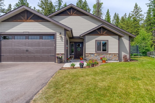 224 Forest Edge Trl, Kalispell, MT 59901 - craftsman house featuring a trampoline, a garage, driveway, a front yard, and stone siding