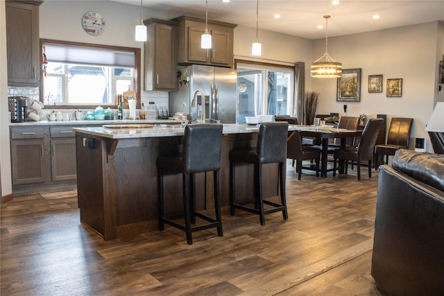 7220 2nd St NW, Havre, MT 59501 - kitchen featuring stainless steel fridge with ice dispenser, recessed lighting, decorative backsplash, a kitchen island with sink, and a breakfast bar area