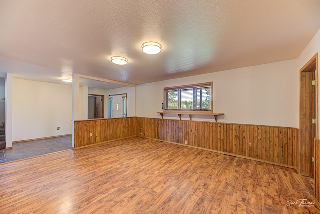 854 State Highway 282, Clancy, MT 59634 - unfurnished room featuring wood finished floors, wood walls, wainscoting, stairs, and a textured ceiling