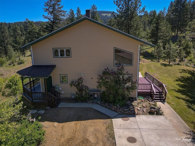 854 State Highway 282, Clancy, MT 59634 - view of side of home with a wooden deck, a patio area, a view of trees, and a yard