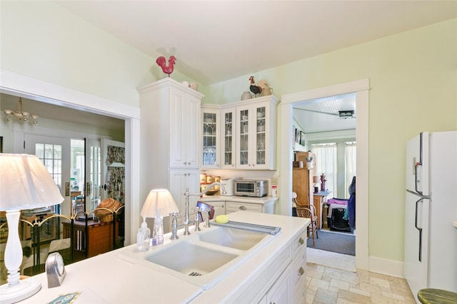 1003 N Burnt Fork Rd, Stevensville, MT 59870 - kitchen featuring freestanding refrigerator, stone tile floors, white cabinets, and glass insert cabinets