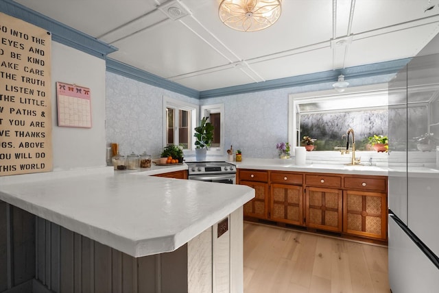 24194 Mt Highway 35, Bigfork, MT 59911 - kitchen with brown cabinets, light wood-style flooring, a peninsula, stainless steel electric stove, and light countertops