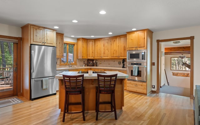 176 Blaine Ridge Rd, Kalispell, MT 59901 - kitchen featuring stainless steel appliances, light wood finished floors, backsplash, a center island, and recessed lighting
