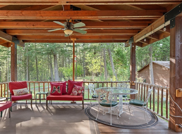 176 Blaine Ridge Rd, Kalispell, MT 59901 - wooden terrace with ceiling fan, outdoor dining area, and a wooded view