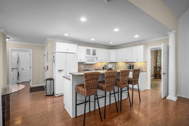 3 Bearberry Ln, Whitefish, MT 59937 - kitchen featuring white appliances, wood finished floors, estacked washer and dryer, crown molding, and white cabinets