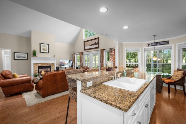 3 Bearberry Ln, Whitefish, MT 59937 - kitchen featuring wood finished floors, white cabinets, a kitchen breakfast bar, a brick fireplace, and recessed lighting