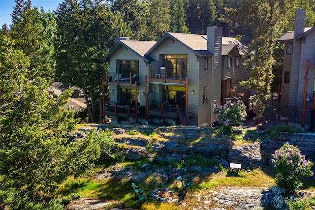 267 Eagle Bend Dr, Bigfork, MT 59911 - rear view of property with a balcony, a fire pit, a wooden deck, and a chimney